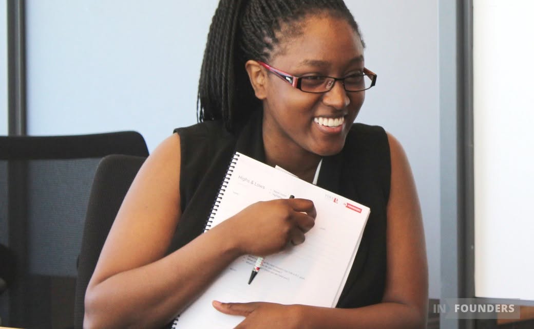 A founder smiling, holding her Highs & Lows mastermind workbook